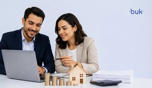 Profesionales sonrientes revisando una laptop junto a casa modelo y monedas sobre cálculo de puntos infonavit. 