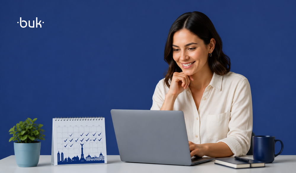 Mujer sonriente trabajando en laptop junto a un calendario de la licencia menstrual cdmx sobre fondo azul.