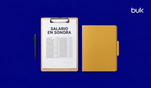 Documento sobre el salario mínimo en Sonora en un portapapeles con una pluma negra y un folder sobre fondo azul.