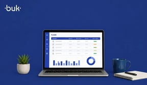 Laptop sobre escritorio mostrando interfaz con gráficas y datos del software de recursos humanos, al costado una planta y taza de café.